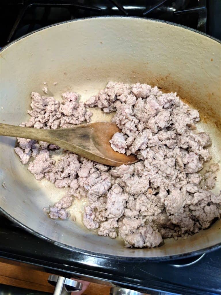 Ground turkey browning on the stovetop in a Dutch oven. 