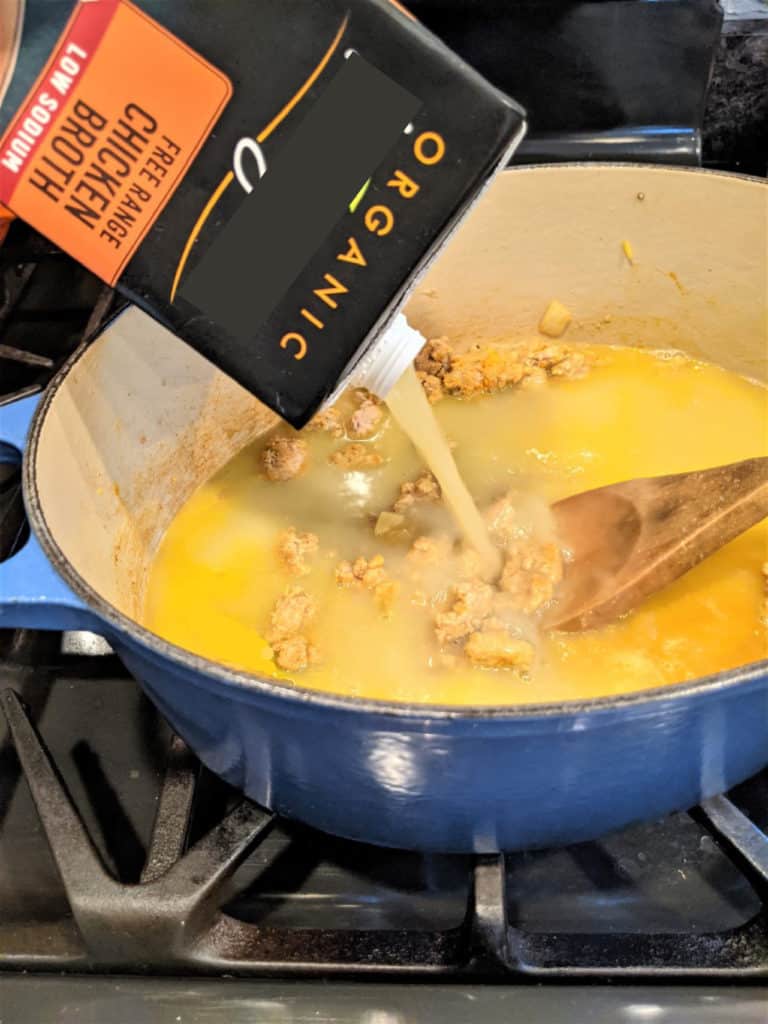 Pouring organic chicken broth into a Dutch oven.