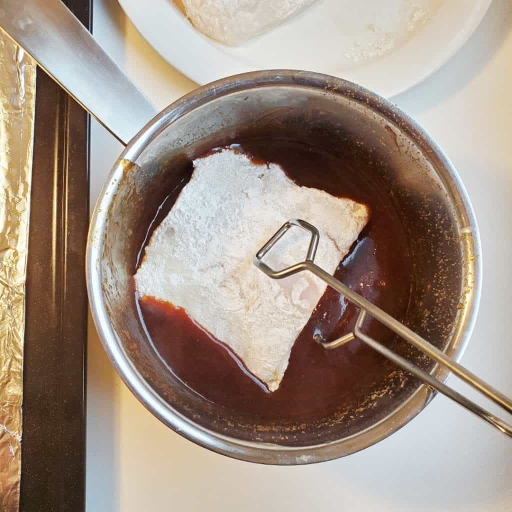Dipping flour coated halibut into homemade teriyaki sauce.