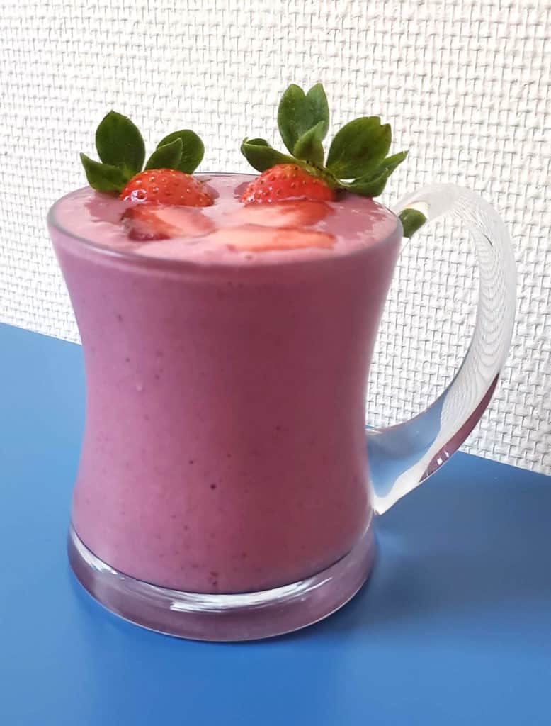 Side view of frozen fruit smoothie in a glass mug.